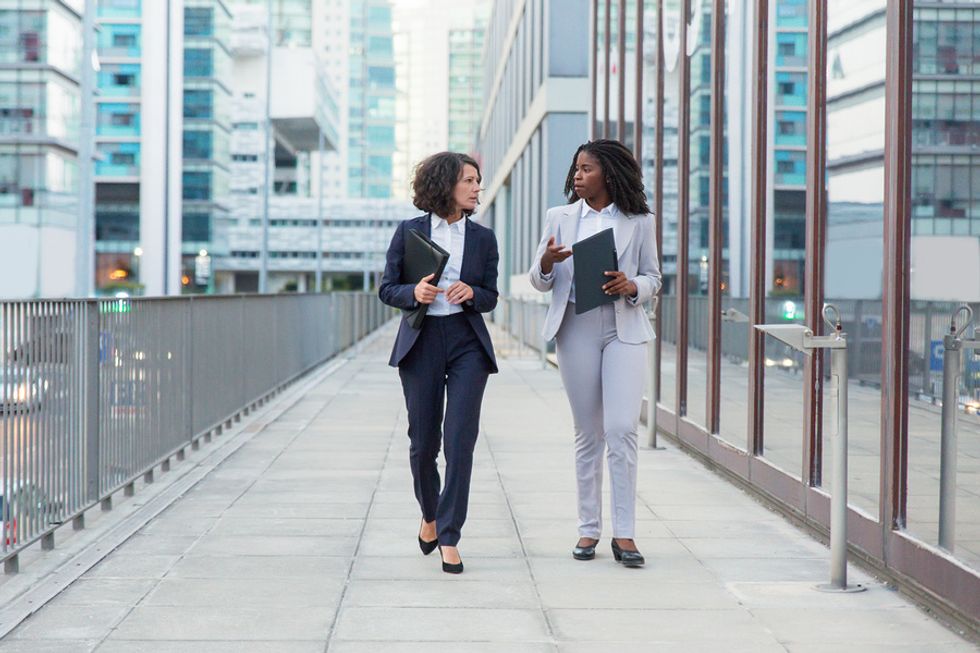 A woman walks with her boss at work and tries to manage up