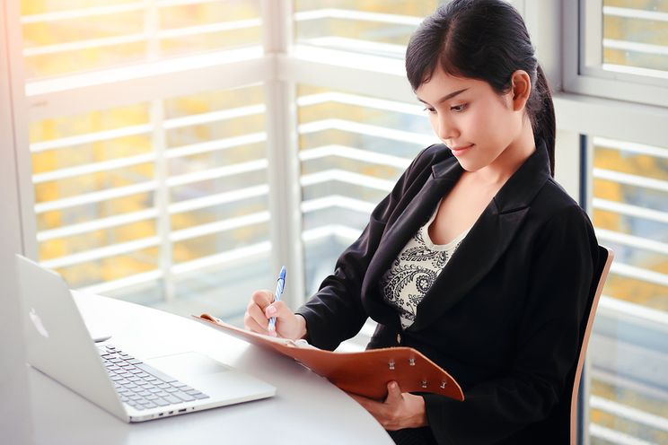 Productive woman working on laptop at her office desk