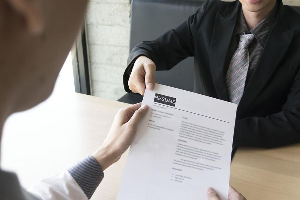 Job applicant hands the hiring manager his resume during an interview