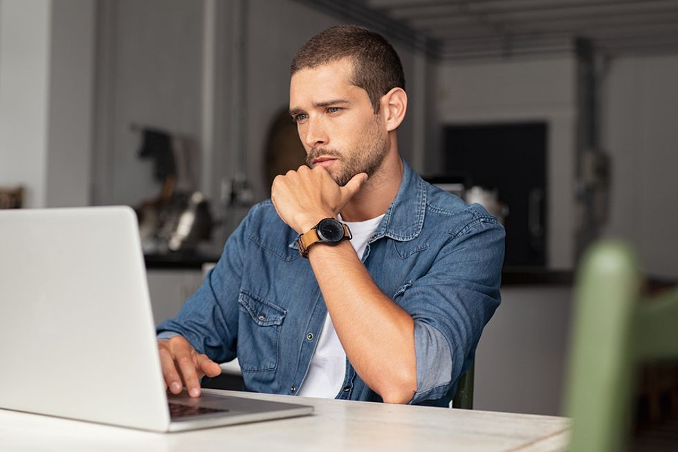 Man at computer thinking about whether or not to leave his job