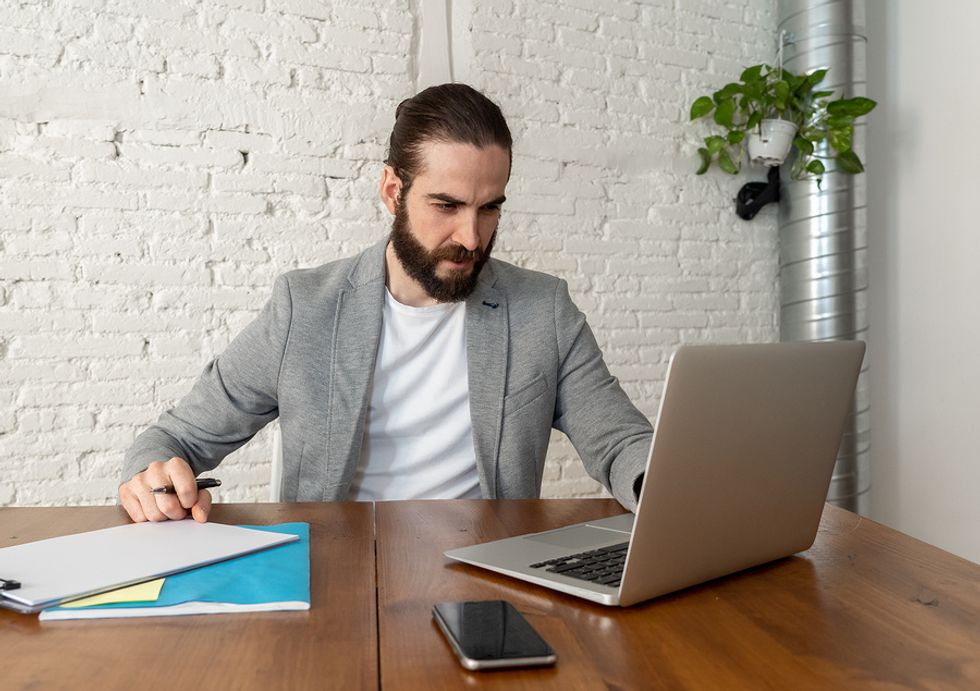 Man looking over his resume on his laptop and formatting it to market his leadership skills