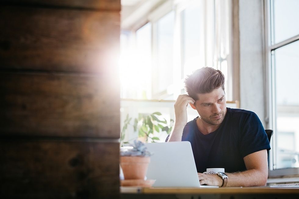 Man on laptop stressed about lying on his resume