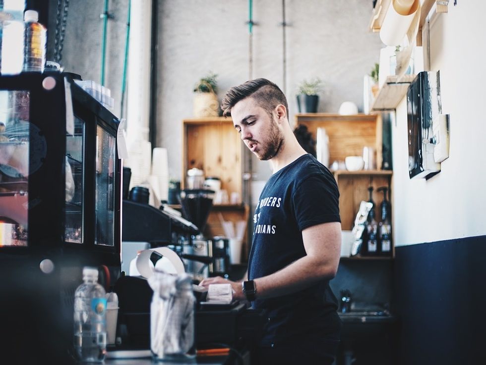 Man works a part-time job as a cashier at a store to boost his resume