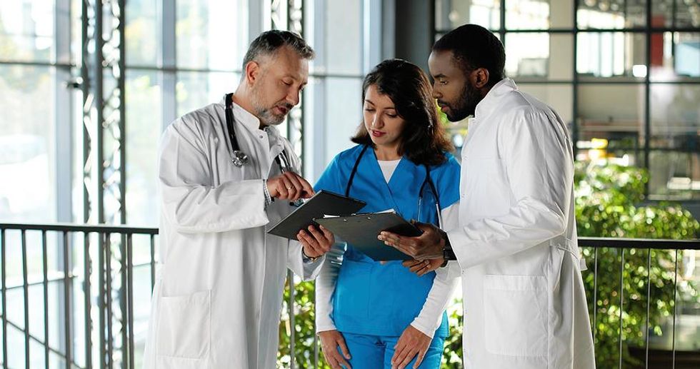 Medical assistant listens to doctors