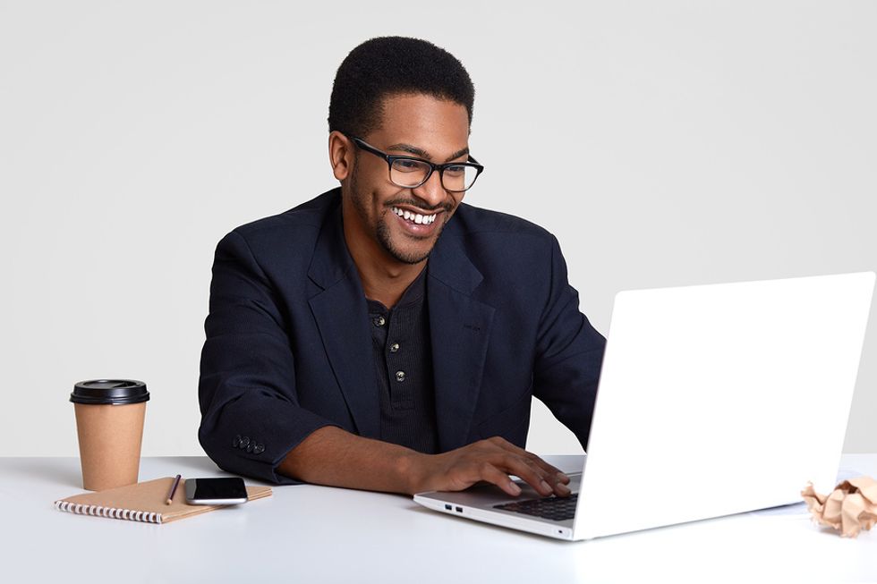 Smiling man working on his resume on his laptop and tailoring it for a leadership job