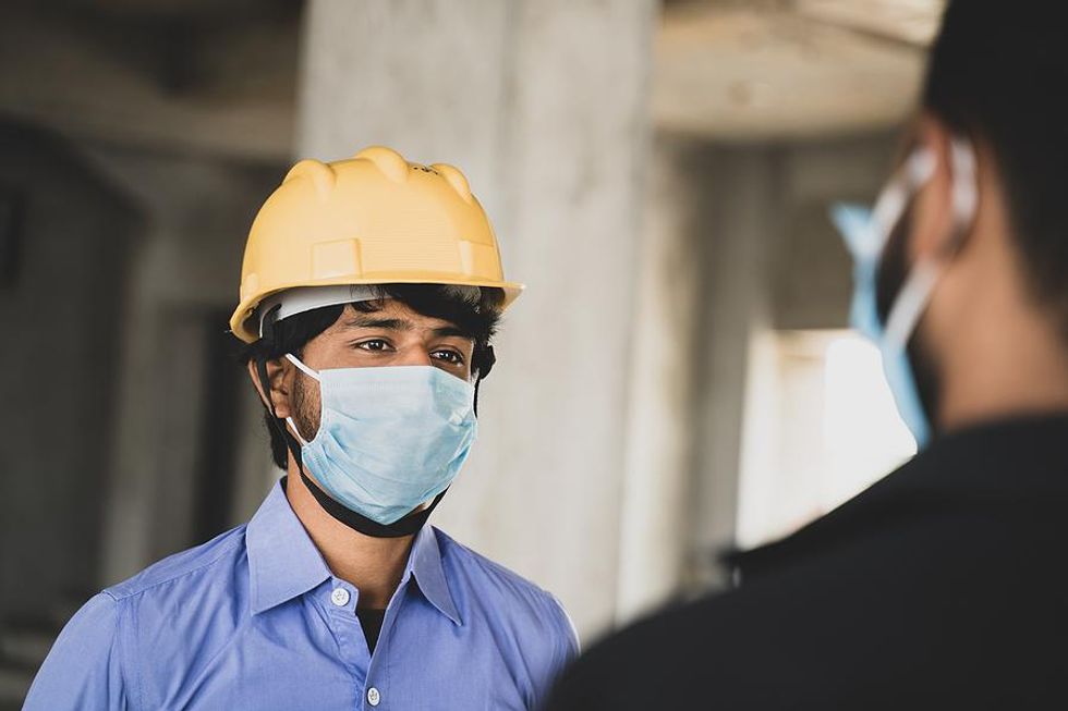 Two employees follow workplace safety guidelines