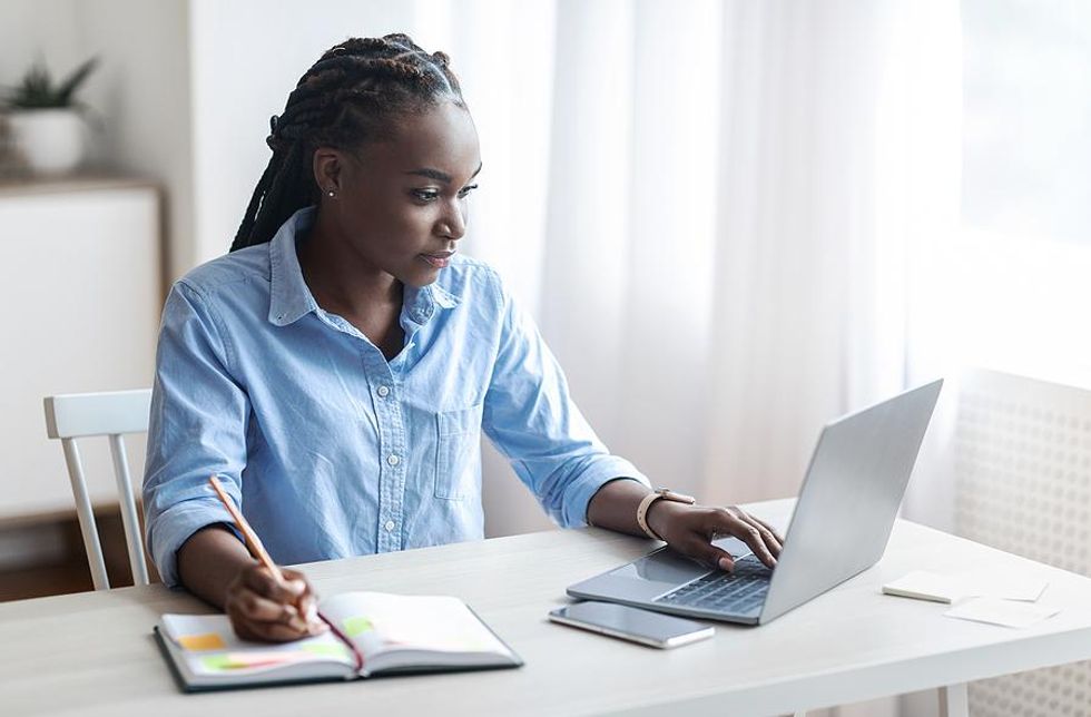 Woman on laptop looks for a job in the fall and takes notes