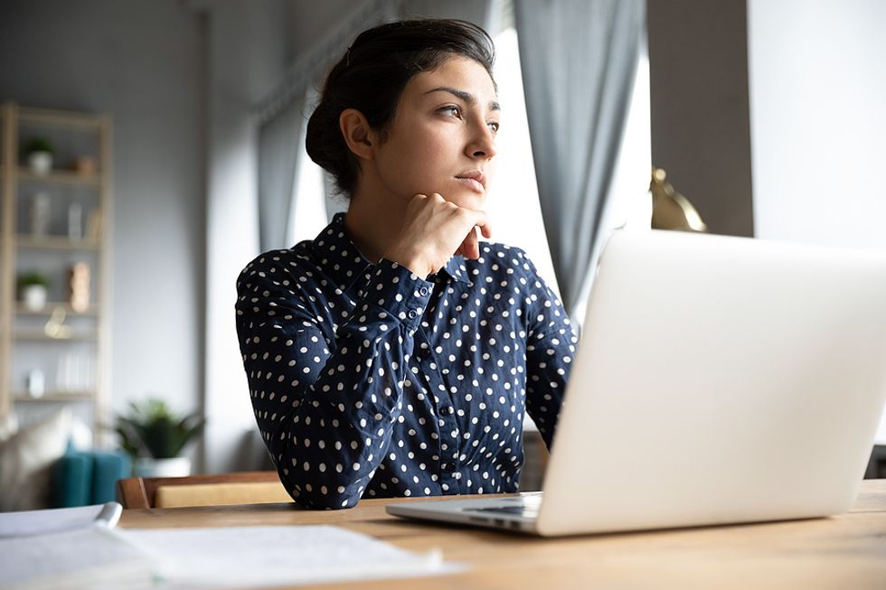 Woman on laptop thinking about lying on her resume