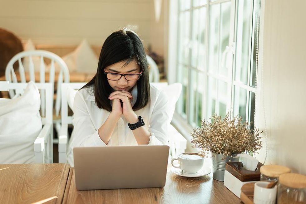 Woman thinks about filling out a job application on her laptop